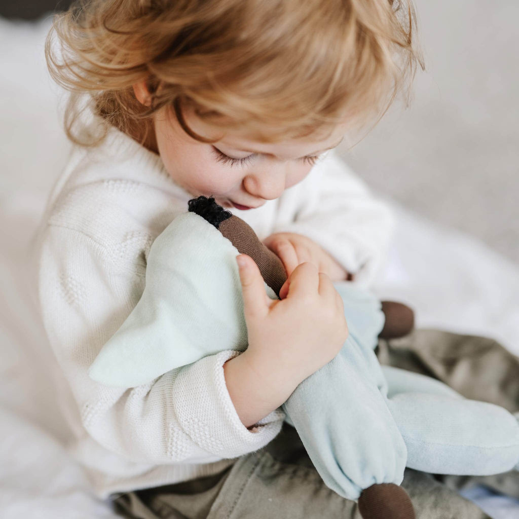 Un bambino coccola la sua bambola di pezza